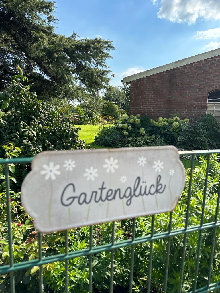 Schild mit der Aufschrift "Gartenglück" an Zaun